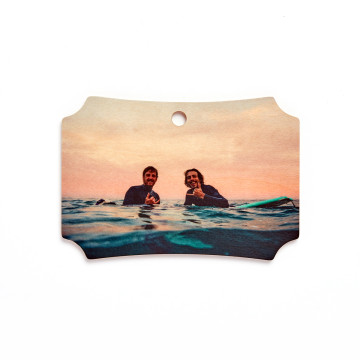 Wooden ornament with an image of two surfers in the ocean