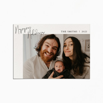 Holiday card with an image of parents smiling with their newborn baby. the title reads "Happy Holidays"