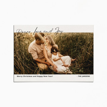 Holiday Card with image of a family sitting in tall grass. At the top is written "Peace, Love, and Joy" in a script font