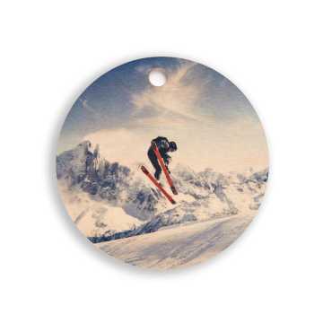 Wooden ornament of a skier mid-jump with mountains in the background