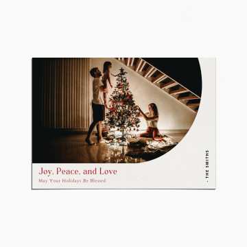 Holiday Card with an image of a family decorating a Christmas tree. the title reads "Joy, Peace, and Love"