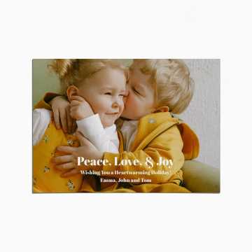 Holiday card with an image of two children embracing. Both are wearing yellow clothing. The title reads "Peace, Love, and Joy"