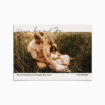 Holiday Card with image of a family sitting in tall grass. At the top is written "Peace, Love, and Joy" in a script font