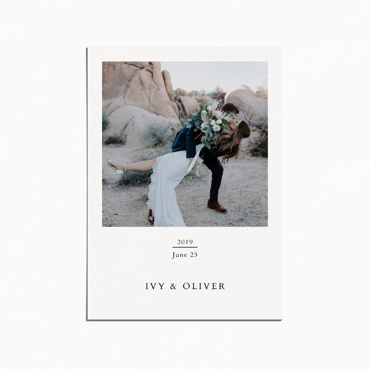 card with an image of a couple on their wedding day, the bride is being dipped. they are in a rocky desert landscape