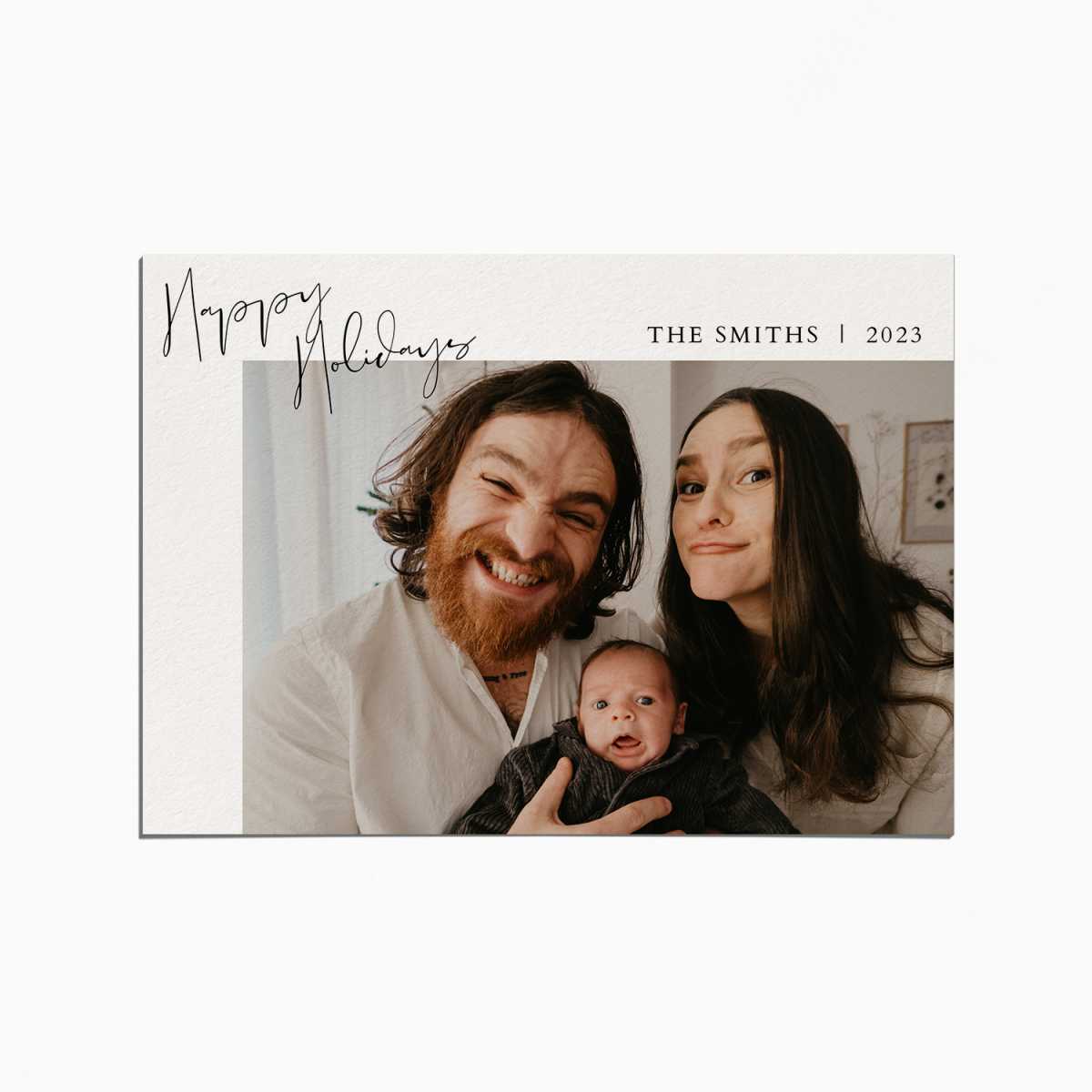 Holiday card with an image of parents smiling with their newborn baby. the title reads "Happy Holidays"