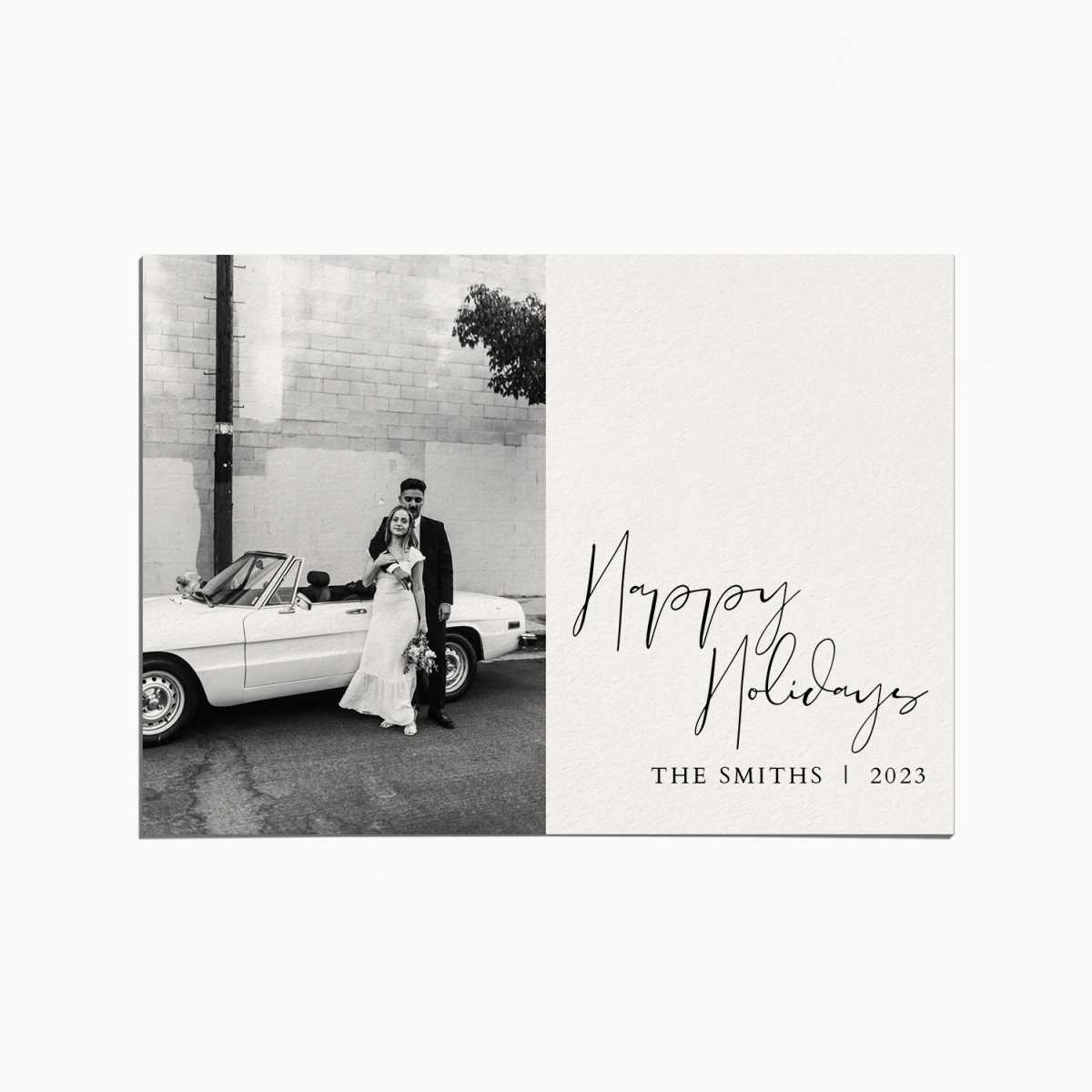 Holiday card with a black and white image of a married couple standing in front of a white convertible car. the title reads "Happy Holidays"
