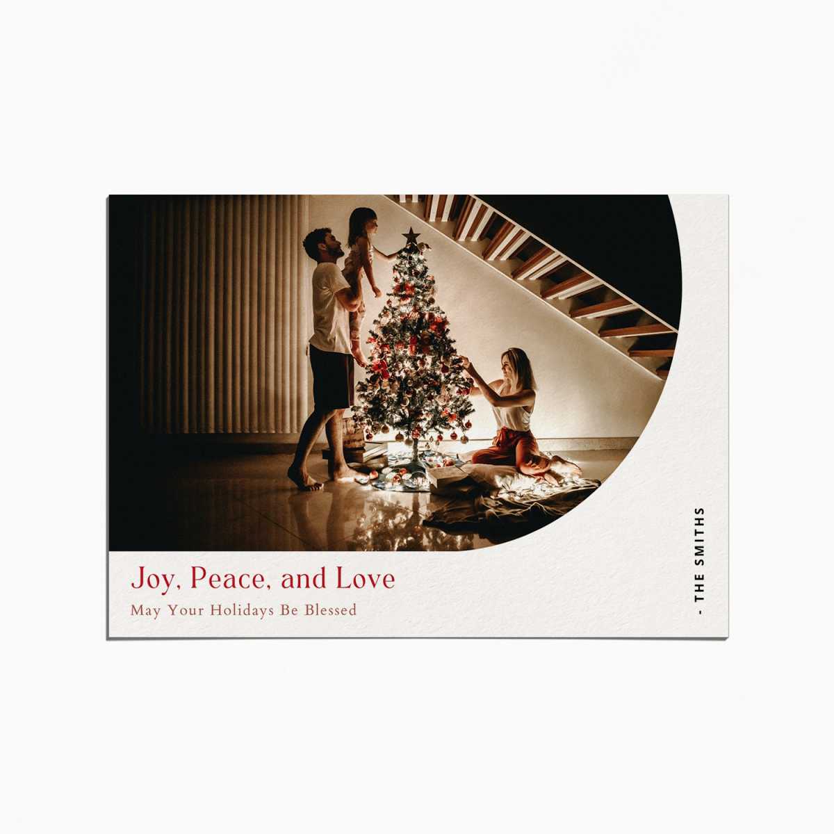 Holiday Card with an image of a family decorating a Christmas tree. the title reads "Joy, Peace, and Love"