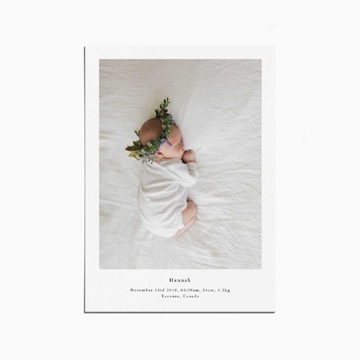 birth announcement card with an image of a baby sleeping and wearing a flower crown